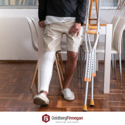 Accident victim sitting a kitchen table next to their crutches.
