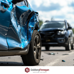 Two heavily damaged vehicles on a highway following a car accident.