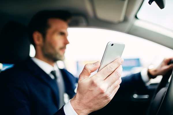 Close up of man using phone while driving car.